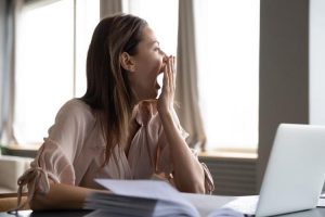 Woman yawning while at her desk